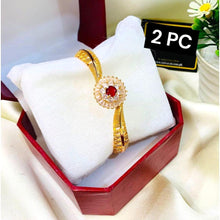 Gold bracelet with red gemstone in a white box on a light background